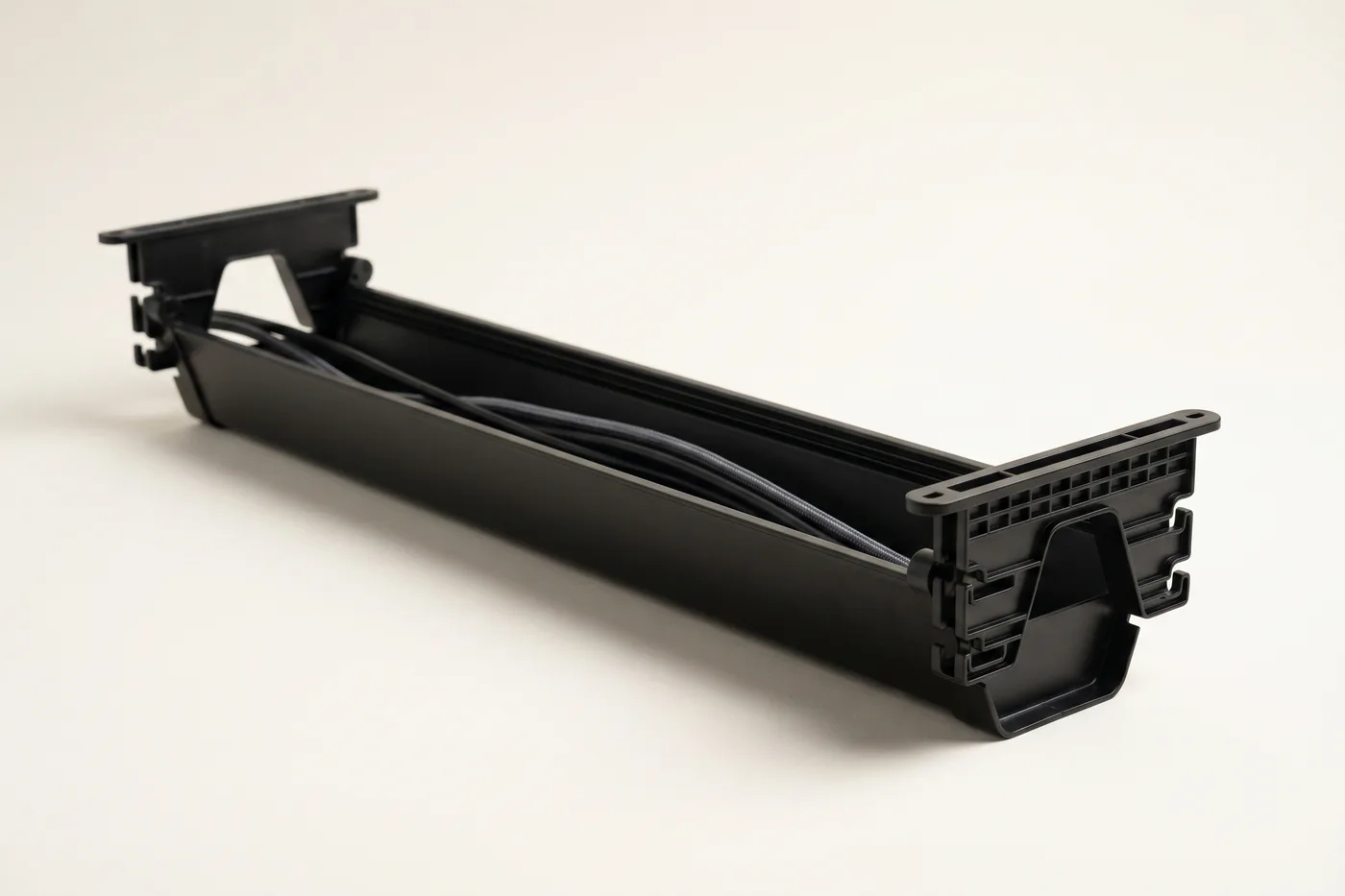 Open under-desk cable management tray in matte black with cables routed inside